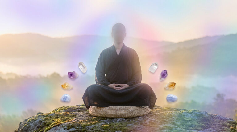 Personne en méditation assise sur un rocher, entourée de cristaux et d'une aura lumineuse colorée.